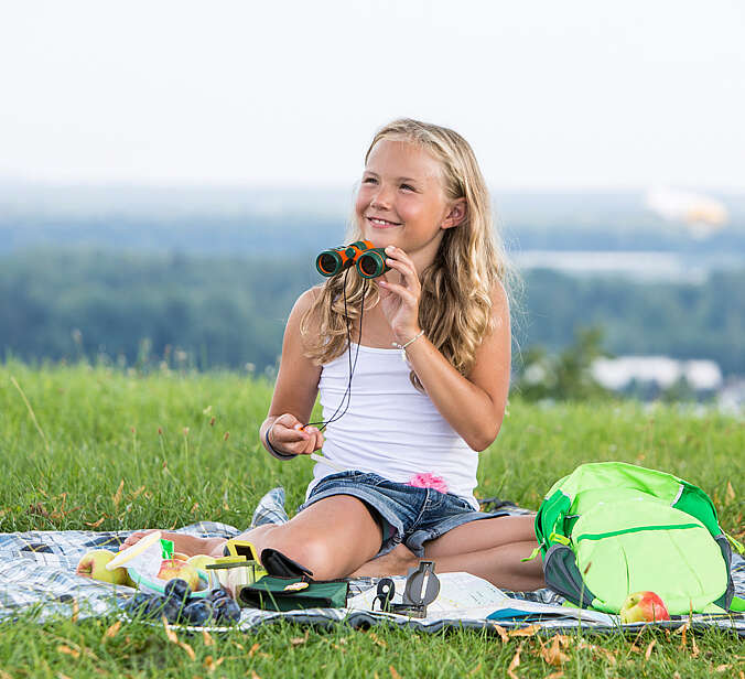 Kind auf Wiese mit Forscherrucksack