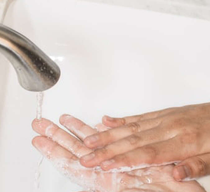Hände unter einem Wasserhahn beim Waschen mit Seife
