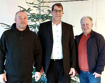 drei Männer vor einem Weihnachtsbaum