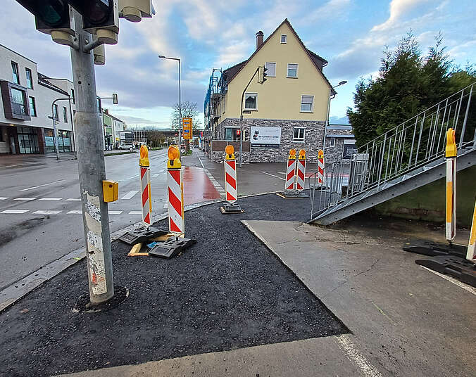 Baustellenabsperrung rot-weiß und Ampelmast auf frischem Asphalt