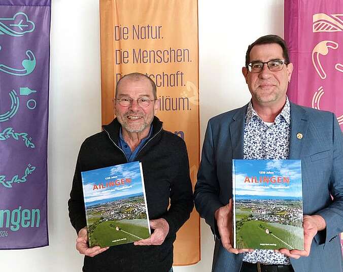 Redaktionsleiter Rainer Barth und Ortsvorsteher Andreas Lipp mit dem Jubiläumsbuch in den Händen