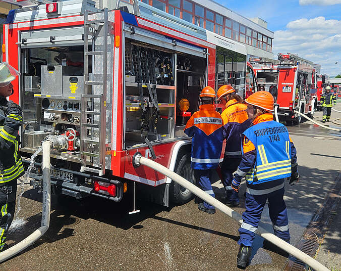 Jugendliche beim Einsatz vor einem Feuerwehrauto.