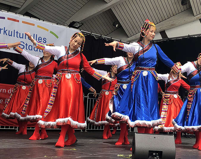 Frauen in roten und blauen Trachtenkleidern tanzen