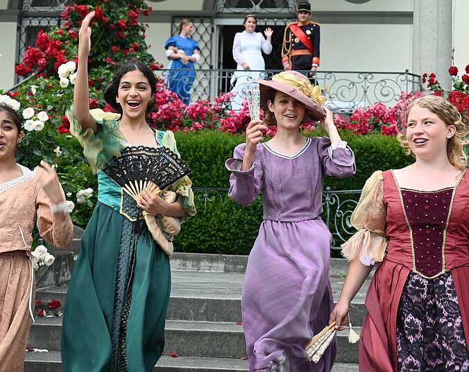 Vier Maedchen mit Kostuemen stehen auf einer Treppe vor dem Schloss Friedrichshafen.