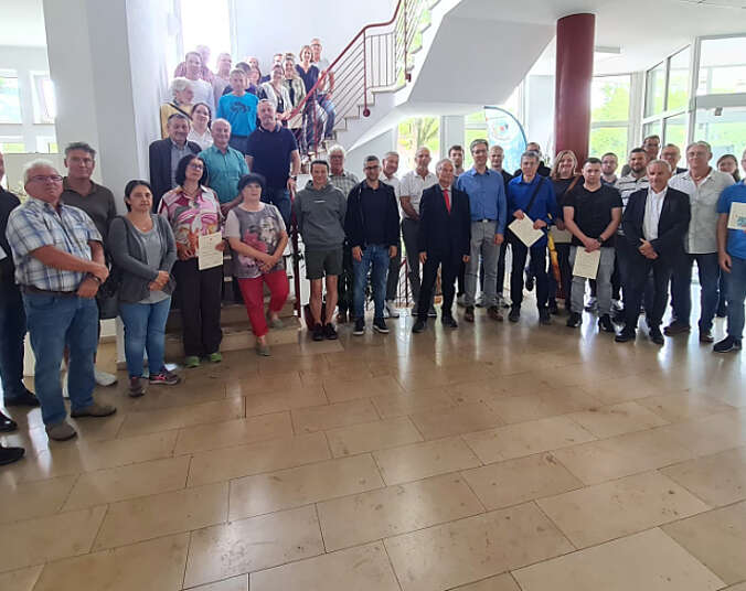 Männer und Frauen stehen in einer Gruppe, teilweise stehen sie auf einer Treppe.