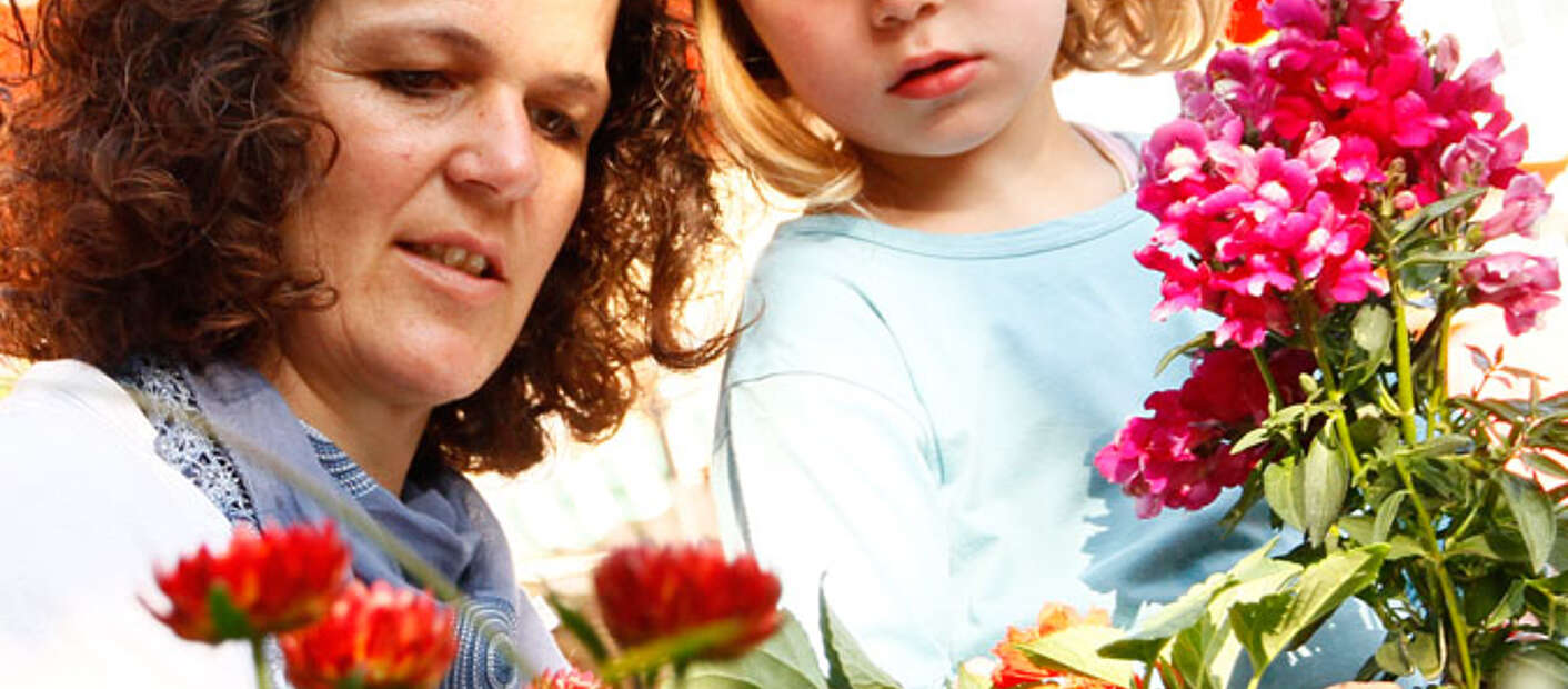 Mutter und Tochter schauen Blumen auf dem Markt an