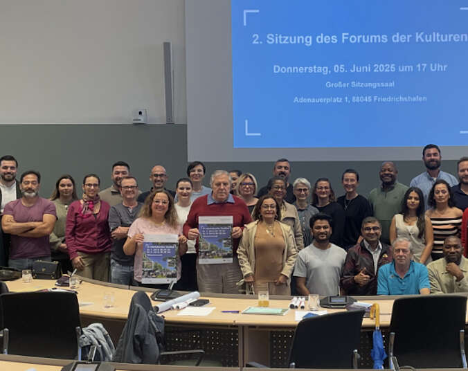 Männer und Frauen stehen hinter Tischen, halten Plakate in Händen.