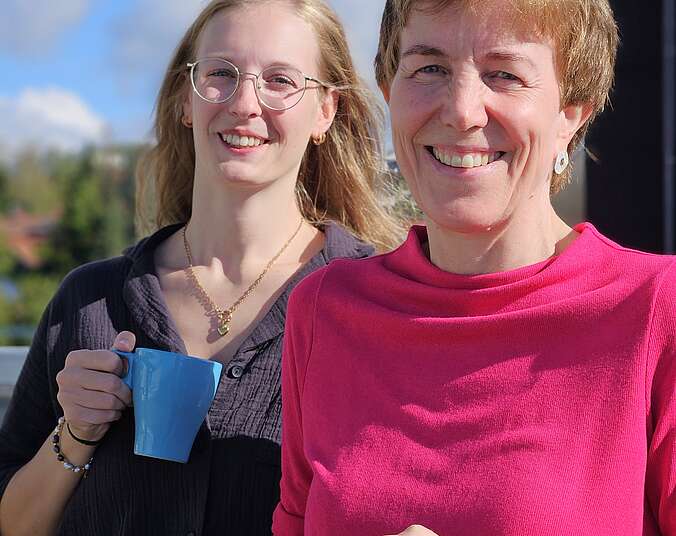 Zwei Frauen mit blauen Kaffeetassen in der Hand
