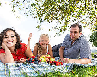 Familie liegt auf der Wieder vor Ihnen Schale mit Obst
