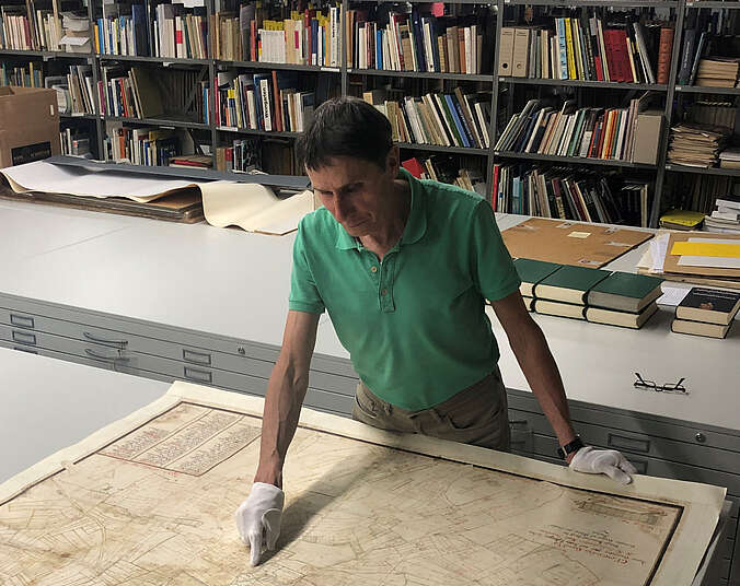 Ein Mann im grünen Hemd steht vor einen großen Karte.