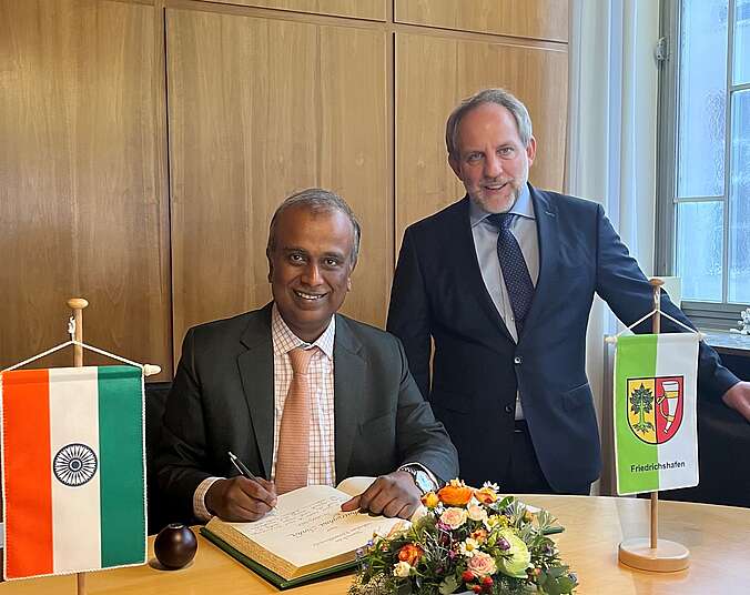 Shatrughna Sinha, Generalkonsul der Republik Indien, sitzend, trägt sich ins Goldene Buch ein, daneben steht OB Simon Blümcke